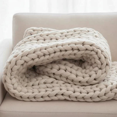 couverture lestée beige pliee sur canape