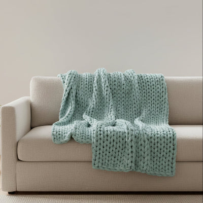 couverture lestee vert pale sur  canape