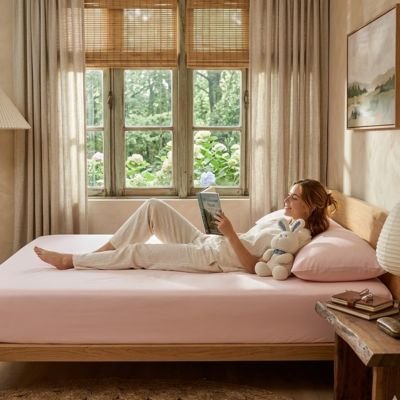 femme lit etendue sur drap housse rose clair