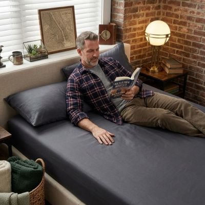 Drap housse homme allonge sur drap housse gris fonce